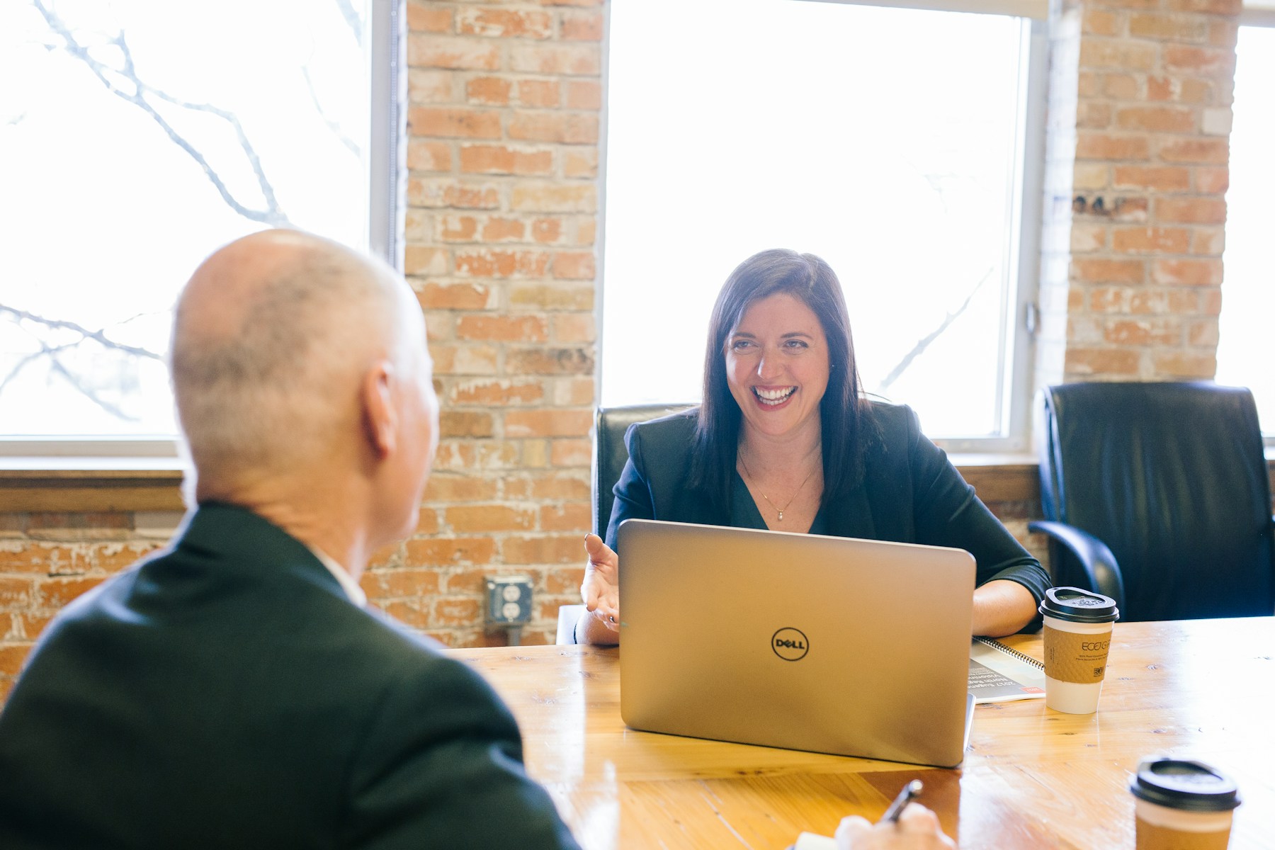 Two people talking across a laptop